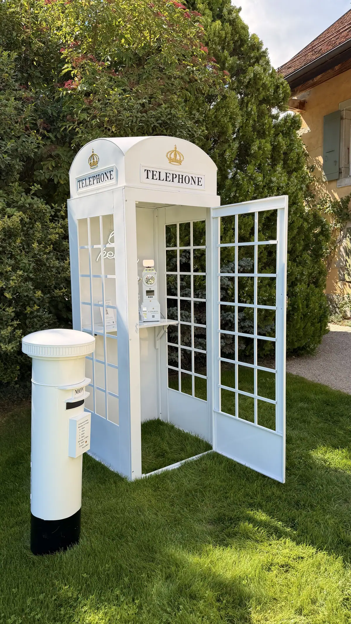 La cabine téléphonique livre d'or COSAM et sa boîte aux lettres sur la pelouse d'un jardin