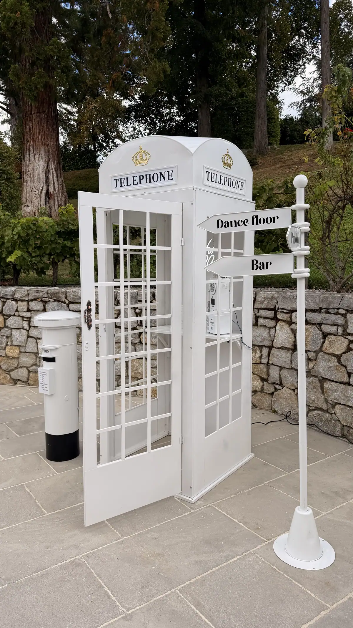 La cabine téléphonique COSAM et son panneau « Dance floor · Bar » devant un mur de pierre