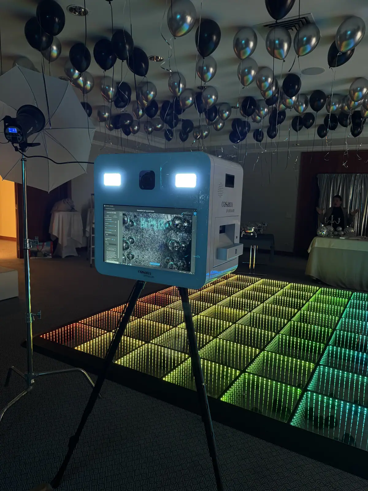 Le photobooth COSAM sur une piste de danse lumineuse, sous un plafond de ballons argentés, à La Barcarolle de Nyon