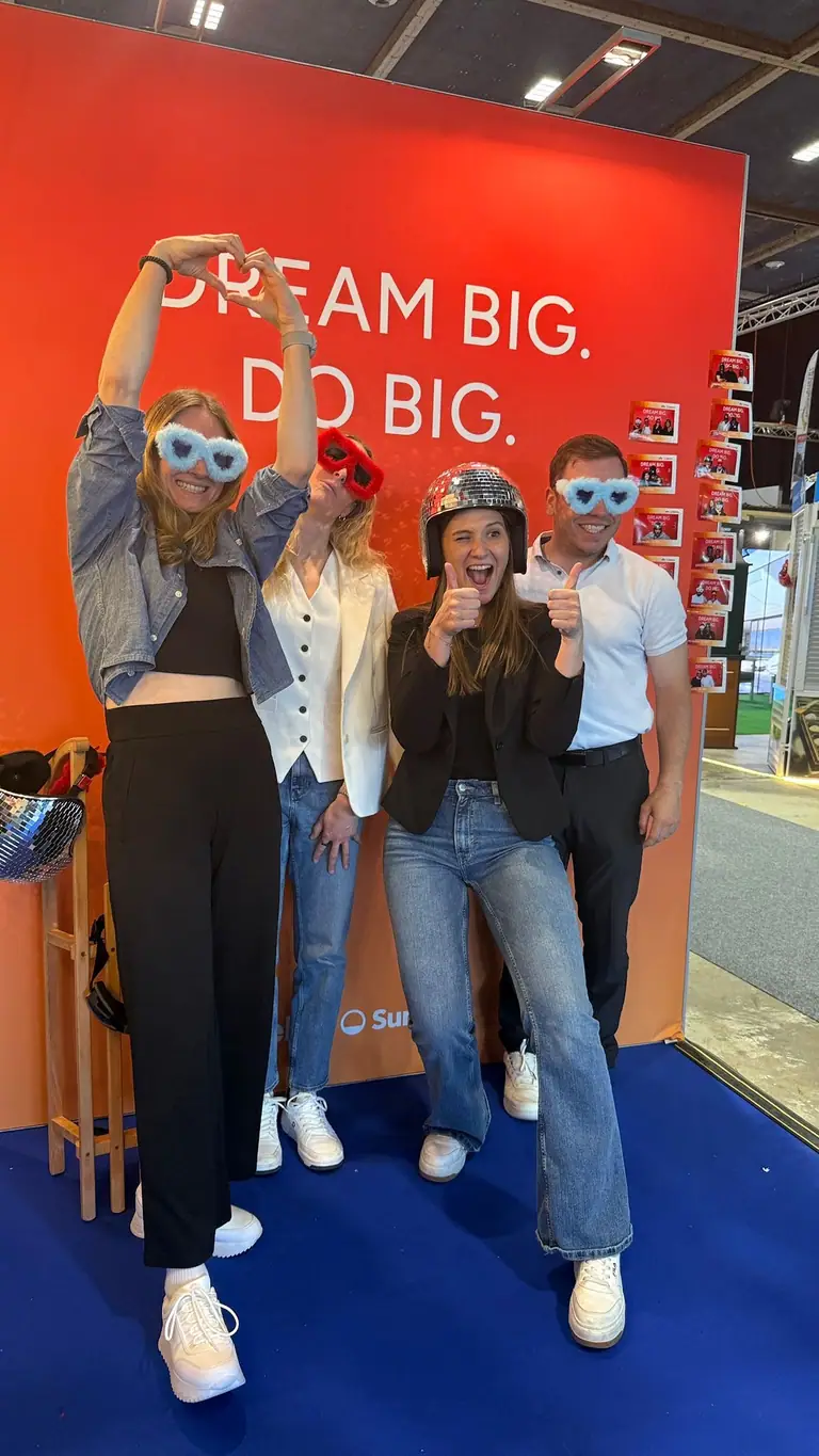 Collaborateurs en lunettes à fourrure et casque disco devant le photobooth COSAM, sur un stand de salon
