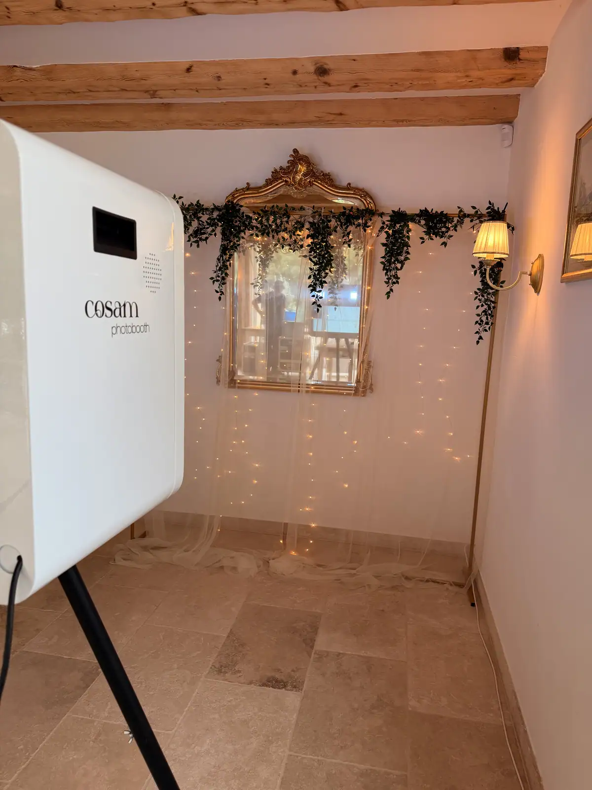 Photobooth habillé d'une arche florale dans une salle de mariage