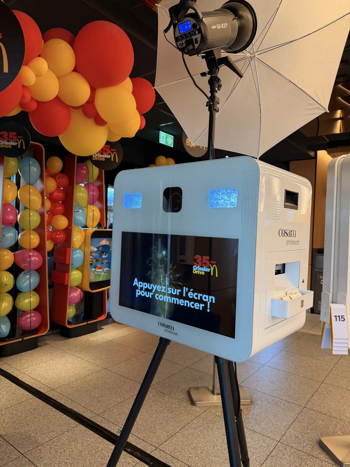 Le photobooth blanc COSAM sous une arche de ballons rouges et jaunes, lors d'une soirée d'entreprise