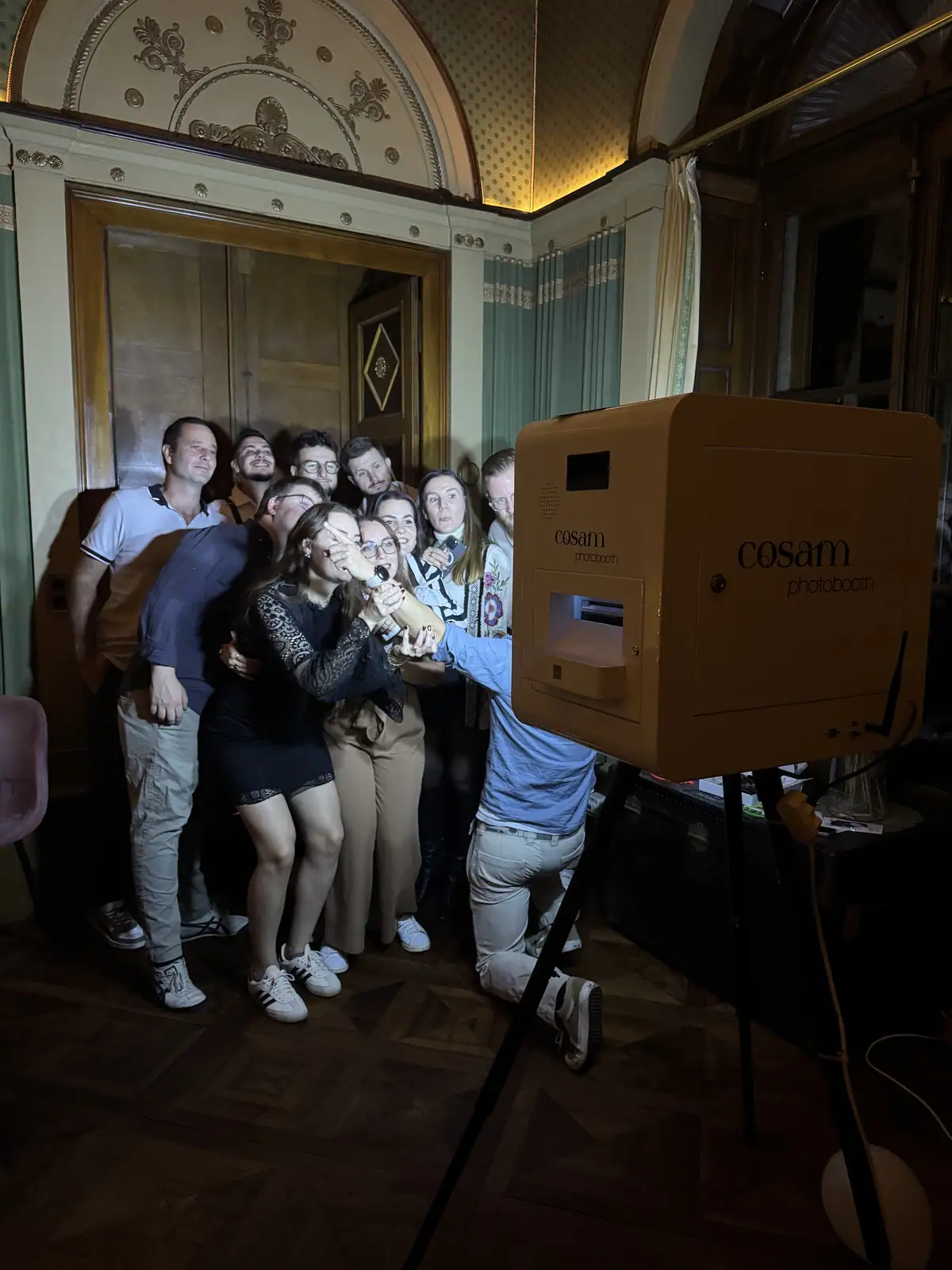 Un groupe d'invités serrés autour du photobooth blanc COSAM à la Villa Castellane, Neuchâtel